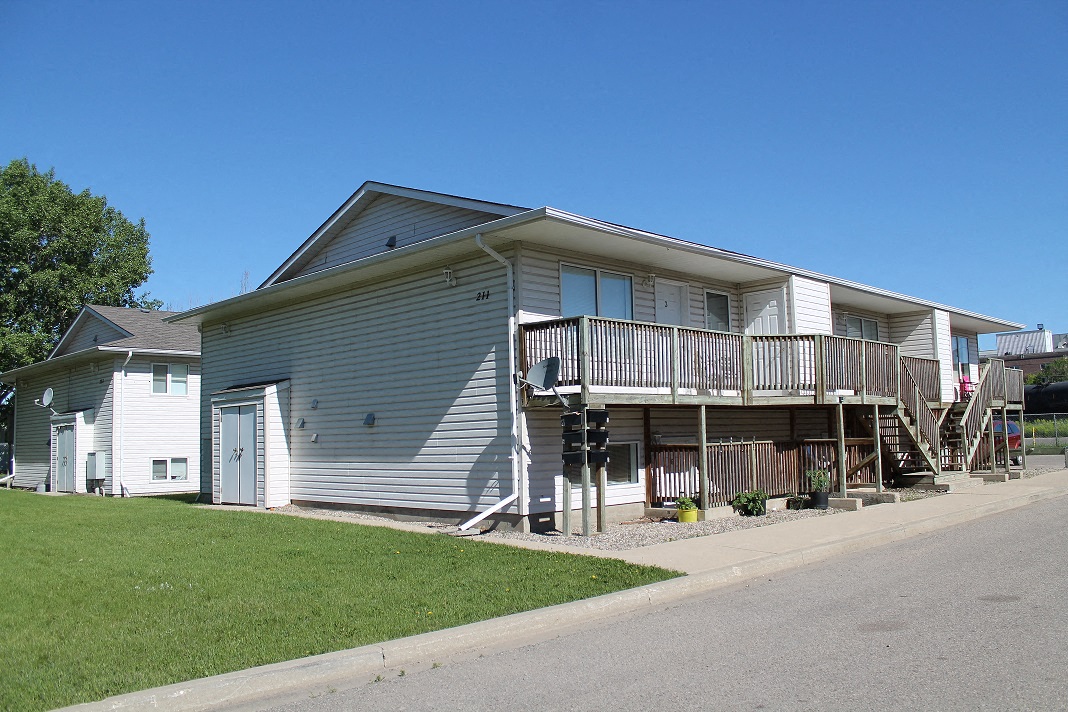 a gray house with a porch and a street in front of it